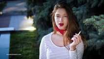 Adorable party girl Irina taking a drag on a Marlboro Red cigarette in the city park