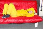 MARA ties, gagges and hoodes herself with cuffs and a ballgag on a sofa wearing sexy yellow rainwear (Pics)