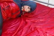 Jill tied and gagged on the bed with cable binders in a black shiny nylon pant and an red/Blue shiny rain jacket (Pics)