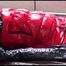 Mara tied and gagged on bed wearing a sexy shiny red down jacket and a blue rain pants (Video)