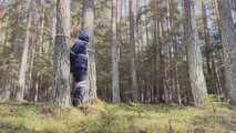 Sebastien breathplay tied up in a puffer jacket among the trees.