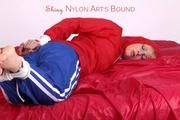 Pia tied and gagged on bed in a shiny bluerainpants and red rainjackert (Pics)