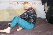PIA ties and gagges herself with a bar and a cloth gag on a bed wearing a sexy green shiny nylon pants and a black rain jacket (Pics)