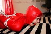 Marlin tied and gagged in red nylon shorts and red cagoule