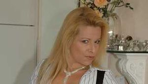 Pierced mature blonde Nina posing in a tight businessdress and stockings in front of the kitchen