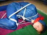 one of our archive girls tied and gagged in a shiny nylon rainsuit