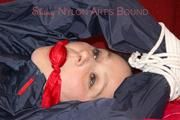 Lucy tied, gagged and hooded with ropes on a sofa wearing a sexy blue/red rainwear combination (Pics)
