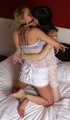 Gagged with a double ballgag, barefoot Dolly and Jessica, tied kneeling face to face, wiggles on the bed