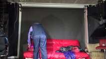 Watching Pia wearing a blue/purple/pink shiny nylon rain suit folding clothes and tidying up the studio (Video)