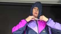 Watching Pia wearing a blue/purple/pink shiny nylon rain suit folding clothes and tidying up the studio (Video)