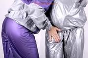 Sophie tied and gagged by Jill on a sofa wearing a shiny silver PVC sauna suit which is slitted by Jill (Pics)