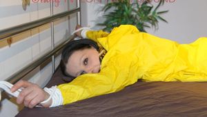 Lucy tied and gagged on bedposts face-down position wearing a sexy yellow shiny nylon shorts and a yellow rain jacket (Pics)