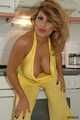 Busty Alexandra posing in a yellow jumbsuit in the kitchen