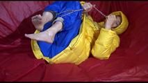Sonja wearing a blue rain pants and a yellow PAMY down jacket while bonding herself an the sofa (Video)