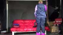 Watching Pia wearing a blue/purple/pink shiny nylon rain suit folding clothes and tidying up the studio (Video)