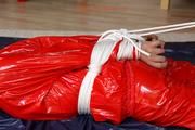 Nina tied and gagged in a shiny red PVC suit