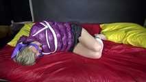 Watching sexy Sonnja wearing a black shiny nylon down skirt and a purple downjacket being tied and gagged with ropes and a ballgag on a bed (Video)