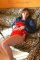 Leonie posing on a leopard sofa wearing a red shiny nylon shorts and an oldschool red/darkblue rain jacket (Pics)