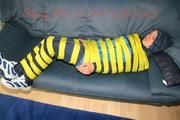 Katharina tied and gagged with tape on a sofa wearing shiny rainwear (Pics)