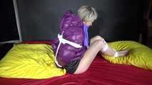 Watching sexy Sonnja wearing a black shiny nylon down skirt and a purple downjacket being tied and gagged with ropes and a ballgag on a bed (Video)