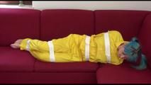 Mara tied and gagged with tape on a sofa wearing a sexy shiny yellow rainwear combination (Video)