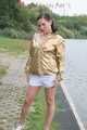 Watching out beautiful archive girl wearing a white shiny nylon shorts and a golden rain jacket posing outdoor (Pics)