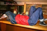 An archive girl tied and gagged on a bar wearing shiny nylon rainwear (Pics)