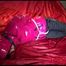 Mara tied, gagged and hooded on a bed wearing a supersexy black rain pants and a pink down jacket (Video)