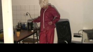 Blonde-haired archive girl being at home wearing shiny nylon rainwear (Video)