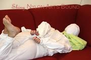 Pia tied and gagged on a sofa wearing a shiny white rain combination (Pics)