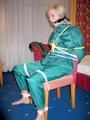 Blonde archive girl tied and gagged in an green shiny nylon rainsuit on a chair (Pics)