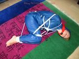 one of our archive girls tied and gagged in a shiny nylon rainsuit
