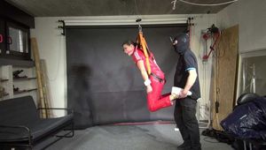 Marie in a custom video suspended in a shiny nylon Jumpsuit