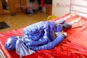 Sonja tied, gagged and hooded on bed with cuffs wearing a sexy grey shiny nylon rain pants and a blue down jacket (Pics)