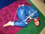 one of our archive girls tied and gagged in a shiny nylon rainsuit