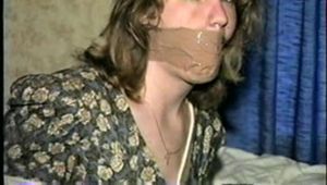 28 YEAR OLD HOUSEWIFE IS MOUTH STUFFED, WRAP TAPE GAGGED, TOE-TIED,  BLINDFOLDED, and HOG-TIED (D57-14)