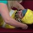 Mara tied and gagged with tape on a sofa wearing a sexy shiny yellow rainwear combination (Video)
