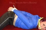 Mara tied and gagged on a sofa wearing a shiny black rain pants and a sexy lightblue down jacket (Video) 