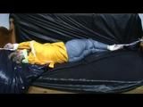 Samantha in a shiny yellow rain jacket and a shiny grey rain trowsers tied and gagged on bed (Video)
