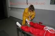 Watching Stella being tied and gagged with ropes and a ballgag on a operating table from Leonie both wearing sexy shiny nylon rainwear (Pics)