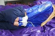 Samantha tied and gagged on bed wearing a shiny darkblue nylon rain pants and a light blue rain jacket (Pics)