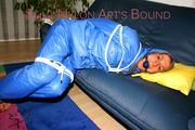 Katharina tied and gagged on a sofa wearing blue shiny downwear (Pics)