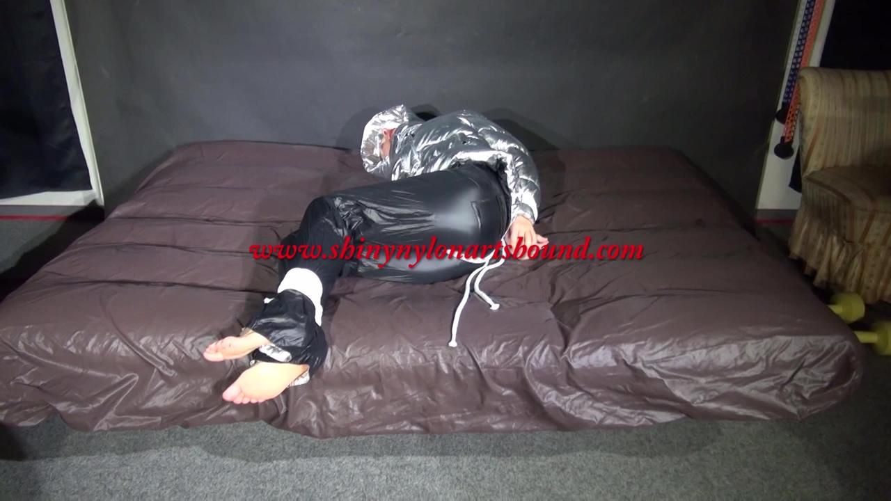 Watching Sexy Sandra Being Tied And Gagged On A Bed With Ropes And A Ballgag Wearing A Supersexy Shiny Black Nylon Pants And A Silver Down Jacket (Video)