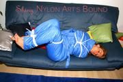 Katharina tied and gagged on a sofa wearing blue shiny downwear (Pics)