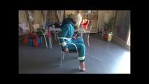 Pia tied and gagged on a chair wearing a shiny green downsuit (Video)