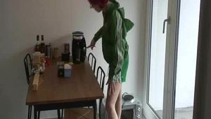 Marlin in the kitchen preparing a coffee wearing a green shiny nylon shorts and a green rain jacket (Video)