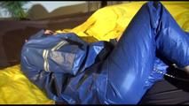Lucy tied and gagged by herself on a bed wearing sexy AGU shiny nylon rainwear (Video)