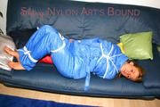 Katharina tied and gagged on a sofa wearing blue shiny downwear (Pics)