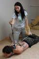 Hazel dominates Gregory, bit-gagged and hogtied with his hands in reverse prayer