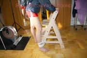 Sonja tied and gagged standing on a chair wearing a sexy red shiny nylon shorts and a darkblue rain jacket (Pics)